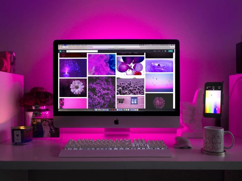 Branding layout designs on a desk workspace beside a graphics monitor screen